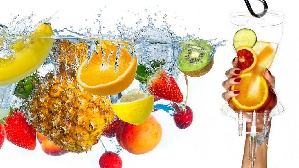 a hand holding a glass of water with fruits falling into it