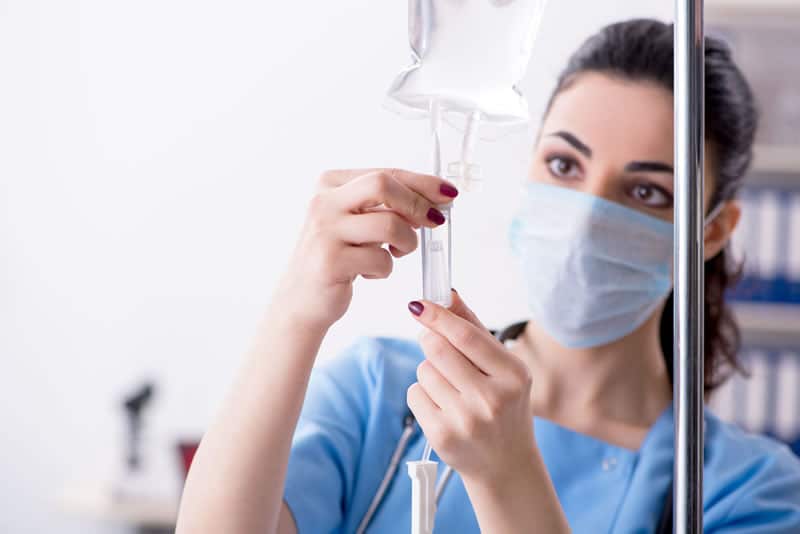 a woman wearing a mask and holding a iv drip