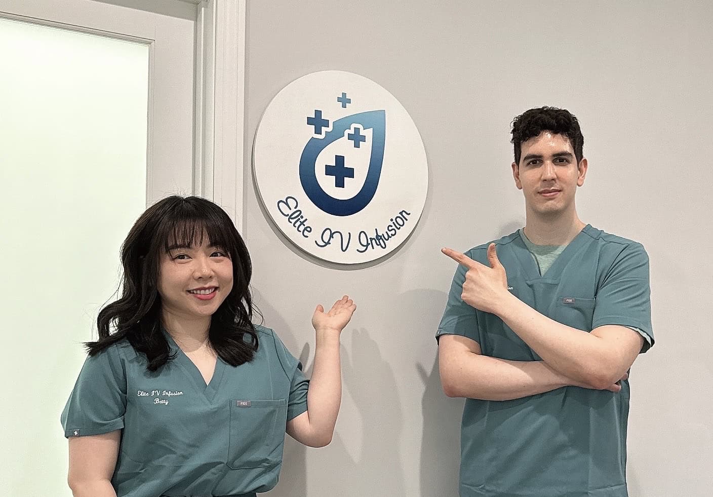 James and Betty in scrubs standing in front of Elite IV Infusion sign ready to give IV therapy services in Lexington, MA