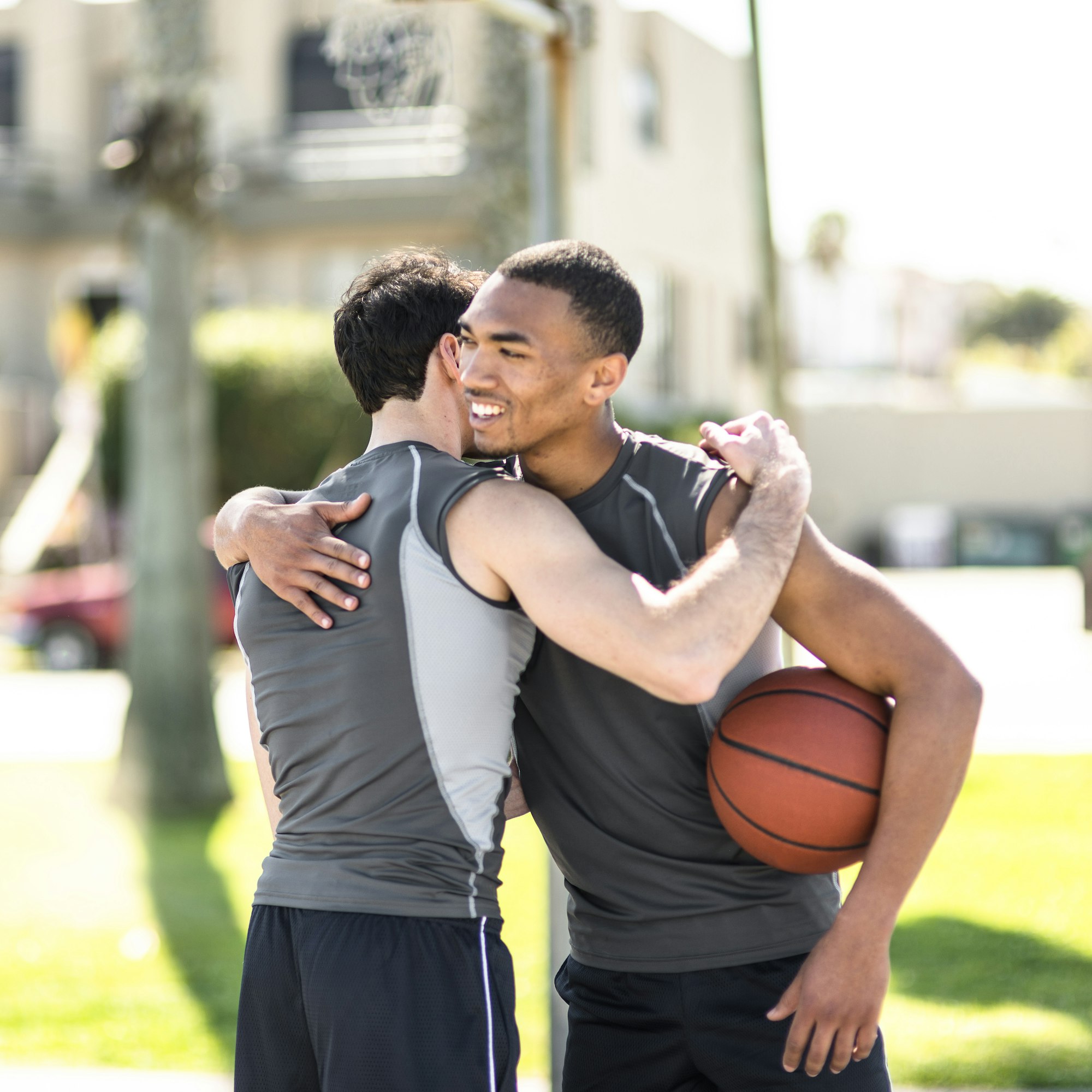 Athletic recovery - Two basketball players embracing outdoors